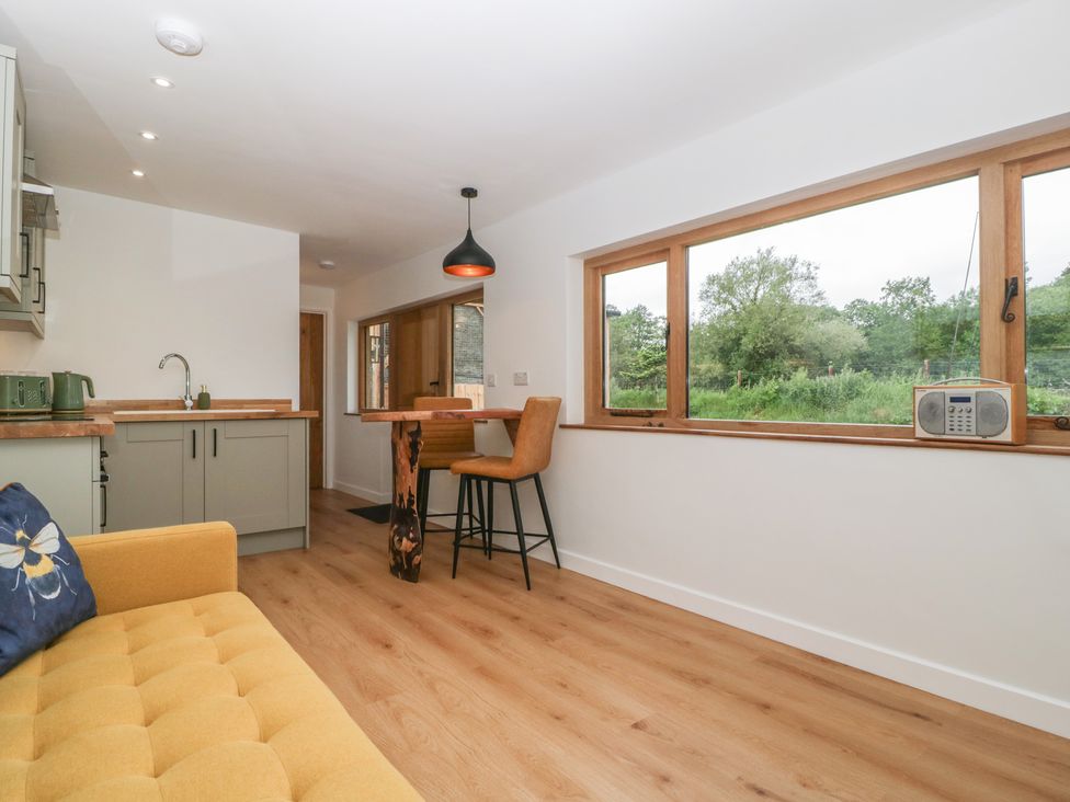 A kitchen with a sink, cabinets and bar stools at Monnow in Pandy near Longtown (hereford)