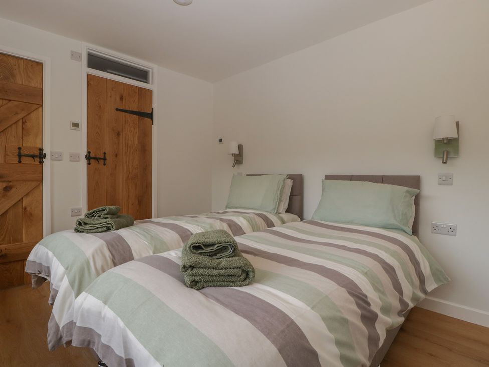 A bedroom with twin beds and towels on top at Monnow in Pandy near Longtown (hereford)