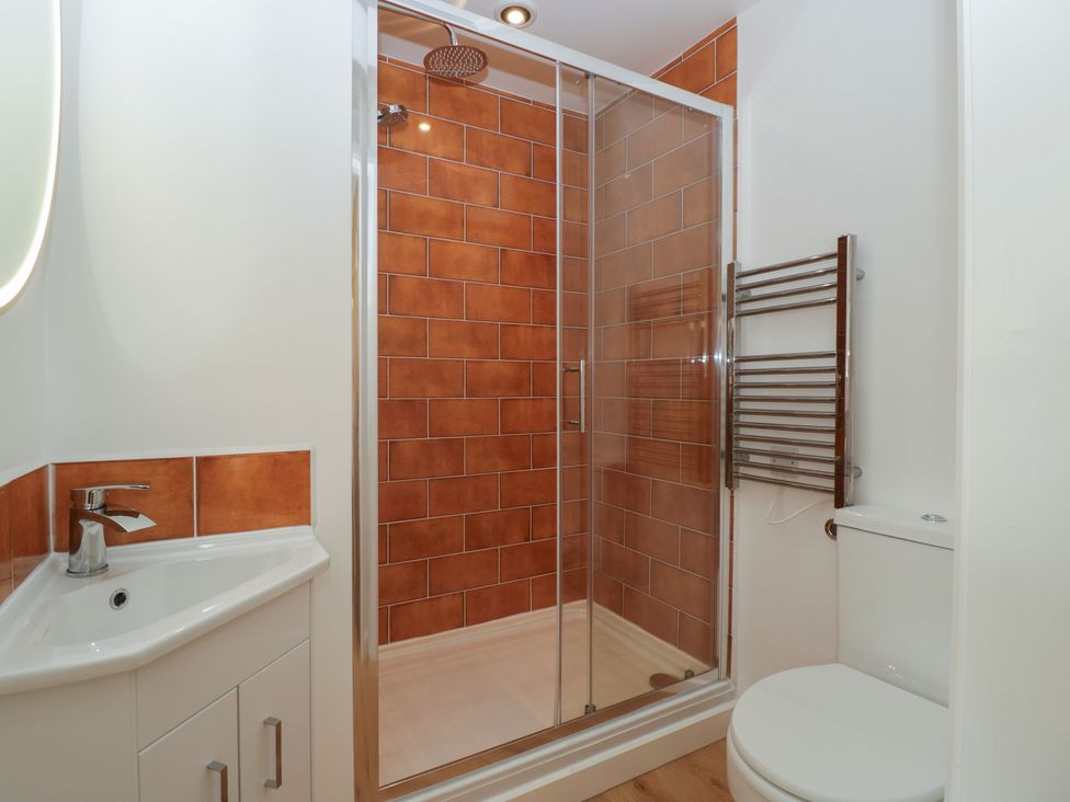 A bathroom with a sink, shower, toilet, and towel rack at Monnow in Pandy near Longtown (hereford)