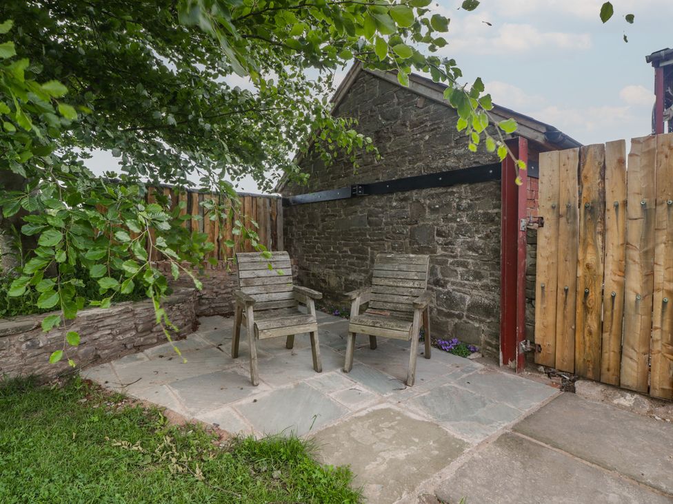 An outdoor seating area with chairs and a stone wall at Monnow in Pandy near Longtown (hereford)