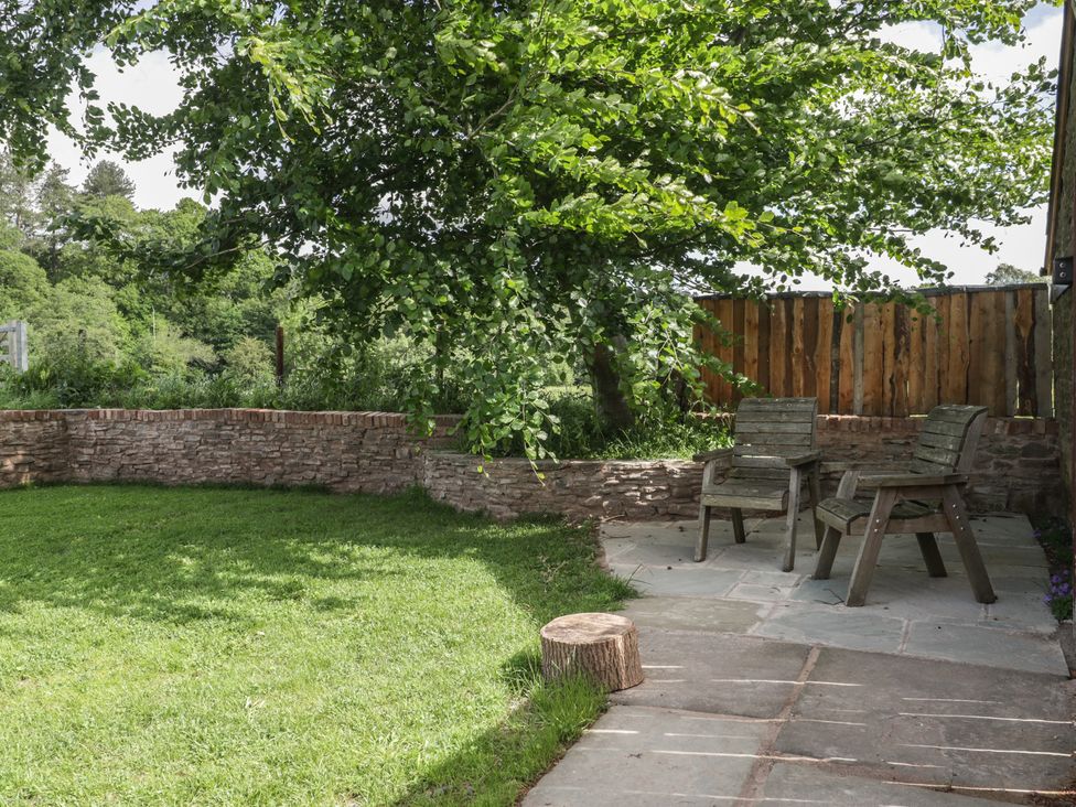 A garden with wooden chairs and a stone wall at Monnow in Pandy near Longtown (hereford)