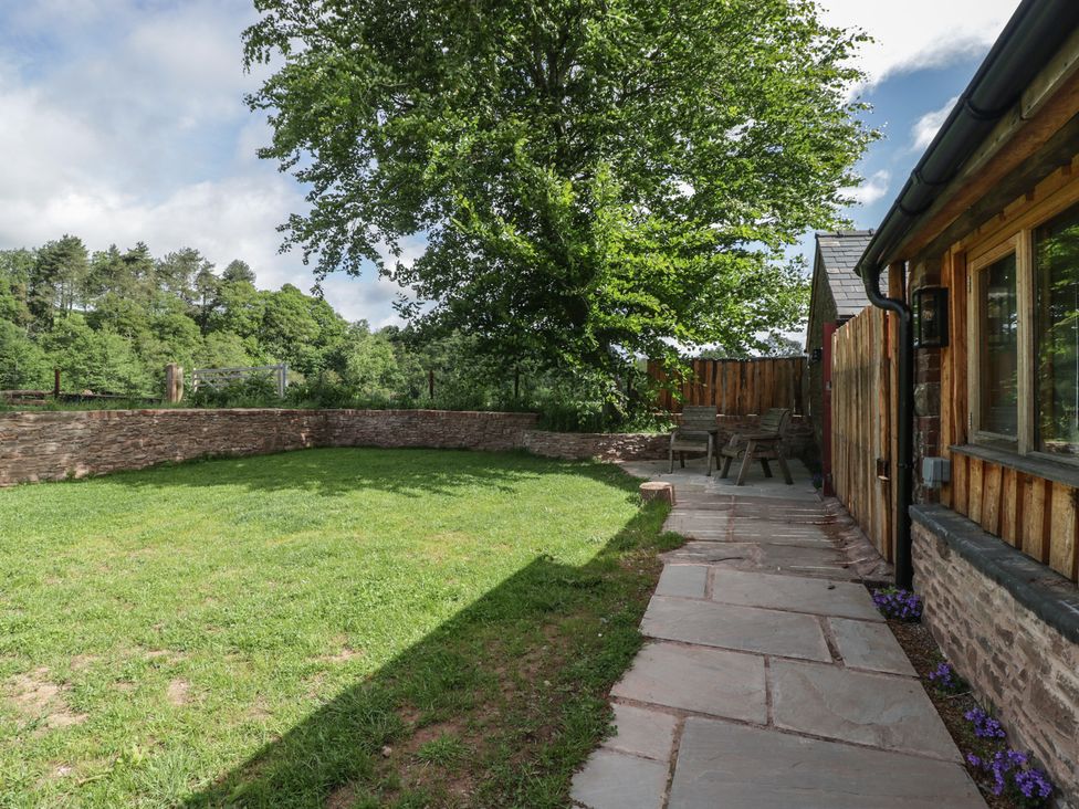 A garden with a stone path and outdoor furniture at Monnow in Pandy near Longtown (hereford)