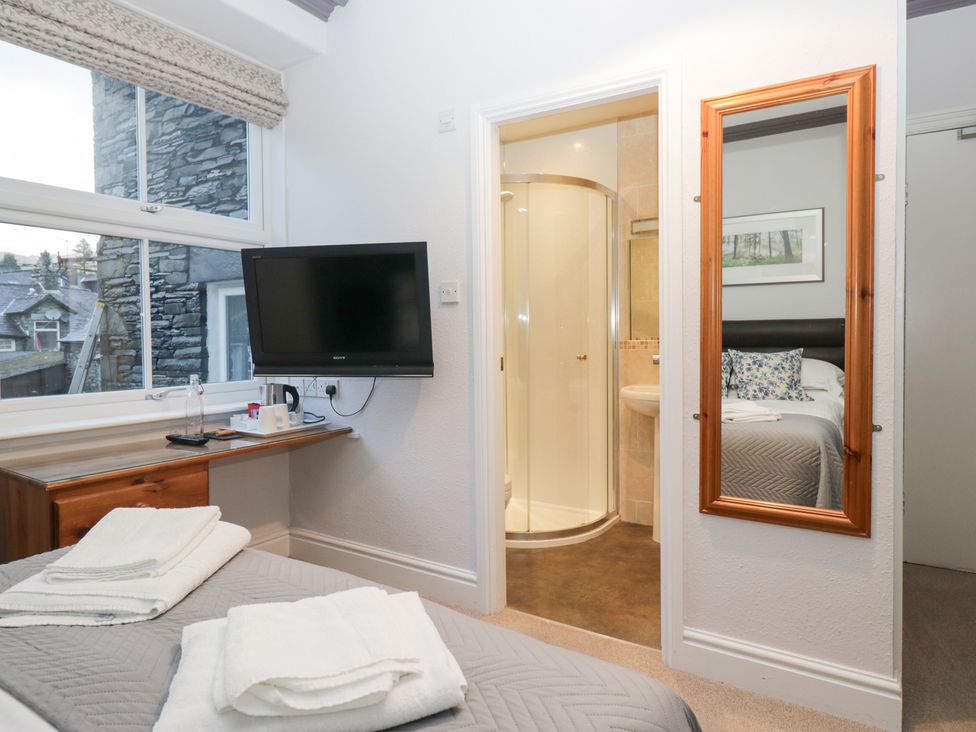 A bedroom with a television and mirror at Norwood House in Ambleside