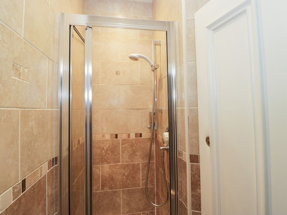 A shower area with tiles and a door at Norwood House Ambleside