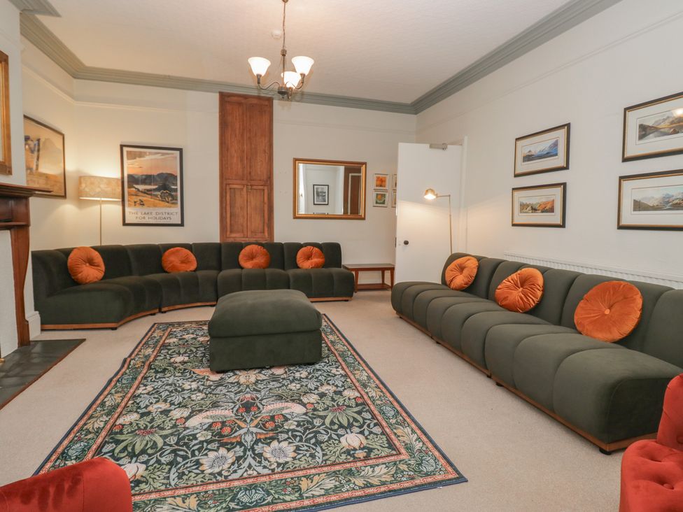 A living room with a green sofa and an ottoman at Norwood House in Ambleside