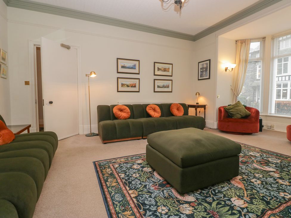 A living room with green sofas and a rug at Norwood House in Ambleside