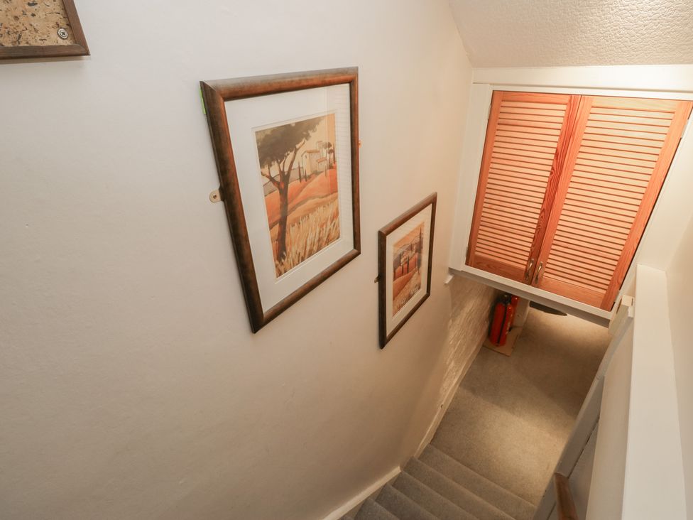 A stairwell with paintings and a fire extinguisher at Norwood House Ambleside