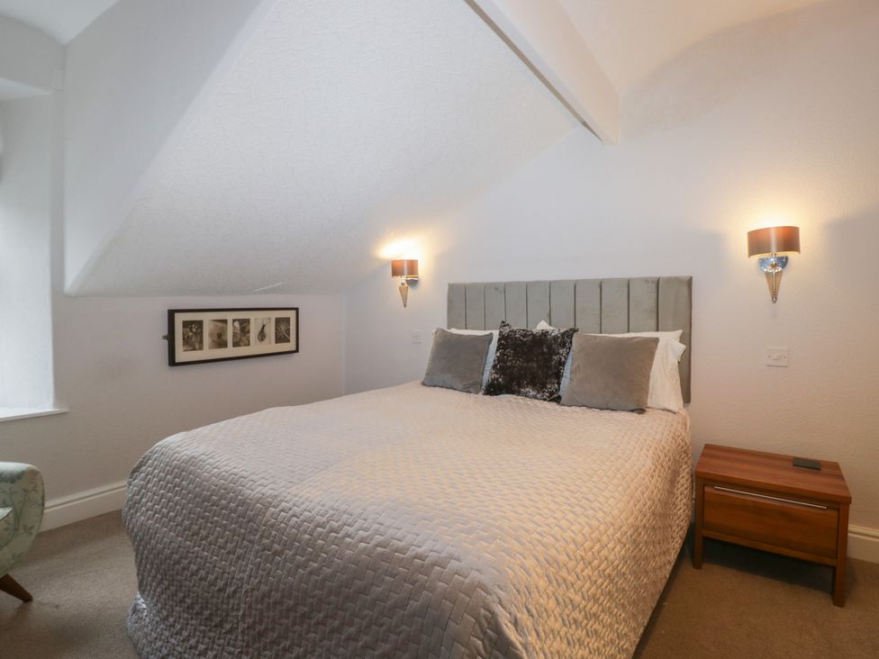 A bedroom with a bed, bedside table, and wall decorations at Norwood House in Ambleside