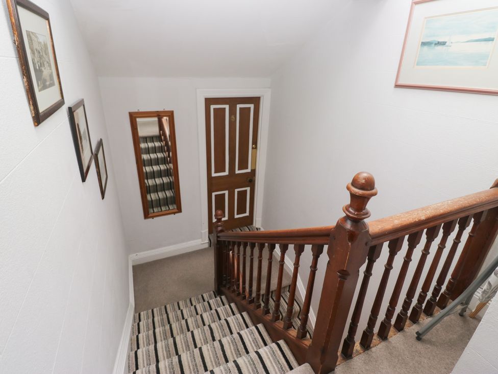 A stairway with wooden railing and photographs at Norwood House in Ambleside