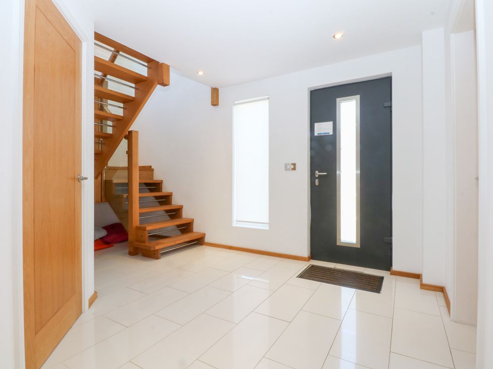A hallway with stairs and a front door at Shearwater in Rhosneigr