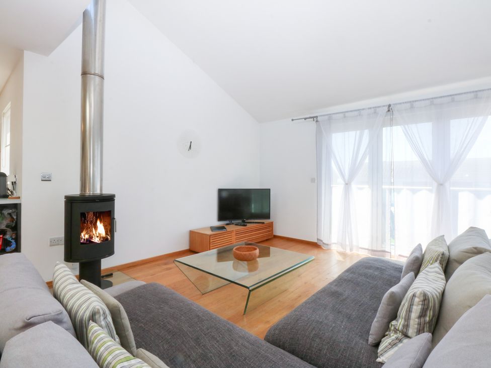 A living room with a wood stove and television stand at Shearwater in Rhosneigr