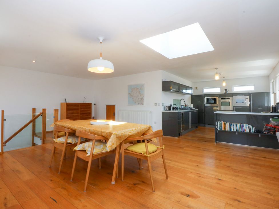A dining area with a table and chairs in an open kitchen at Shearwater Rhosneigr