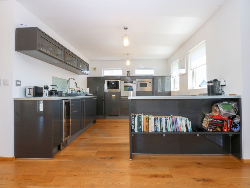A kitchen with cupboards, sink, and appliances at Shearwater in Rhosneigr