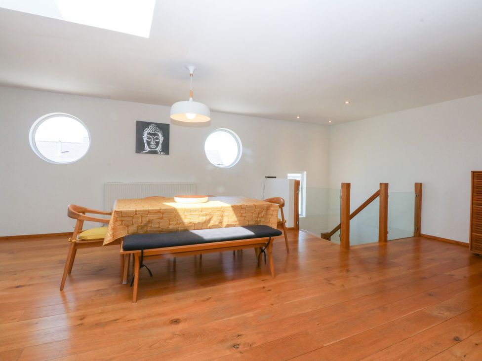 A dining room with circular windows and a table at Shearwater in Rhosneigr
