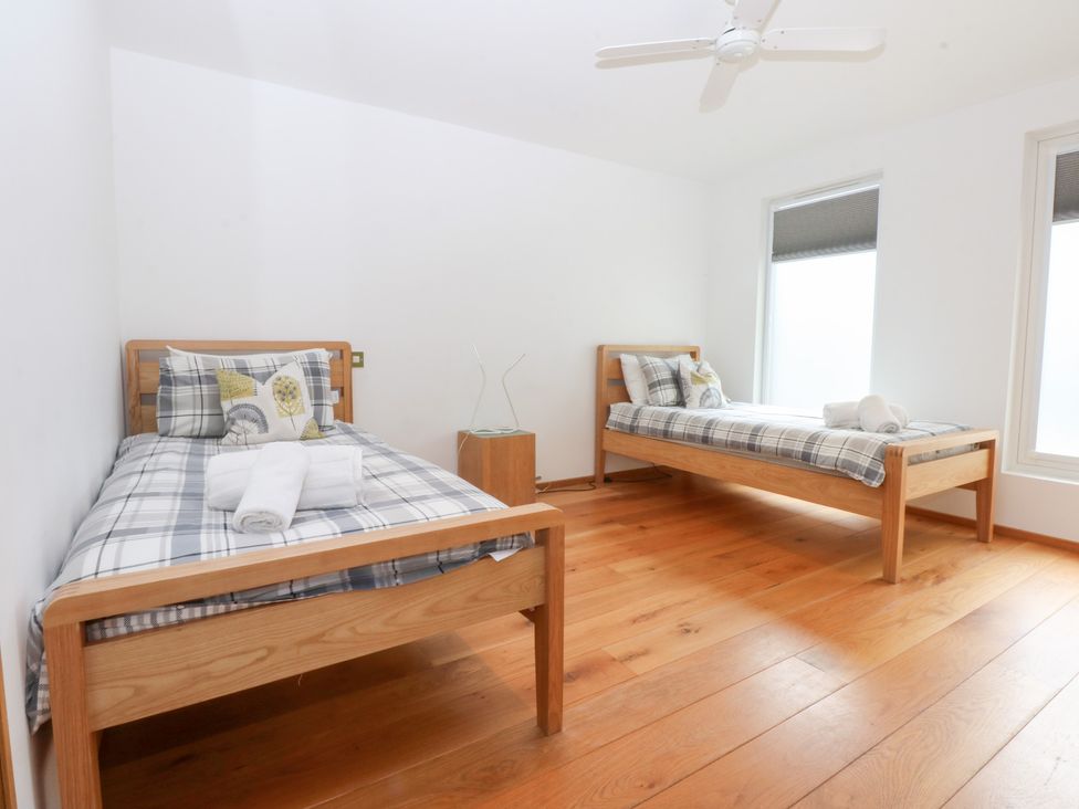 A bedroom with two single beds and a nightstand at Shearwater in Rhosneigr