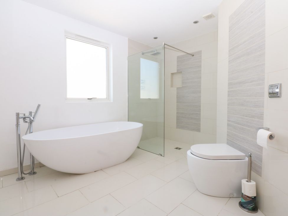 A bathroom featuring a bathtub, shower, and toilet at Shearwater in Rhosneigr
