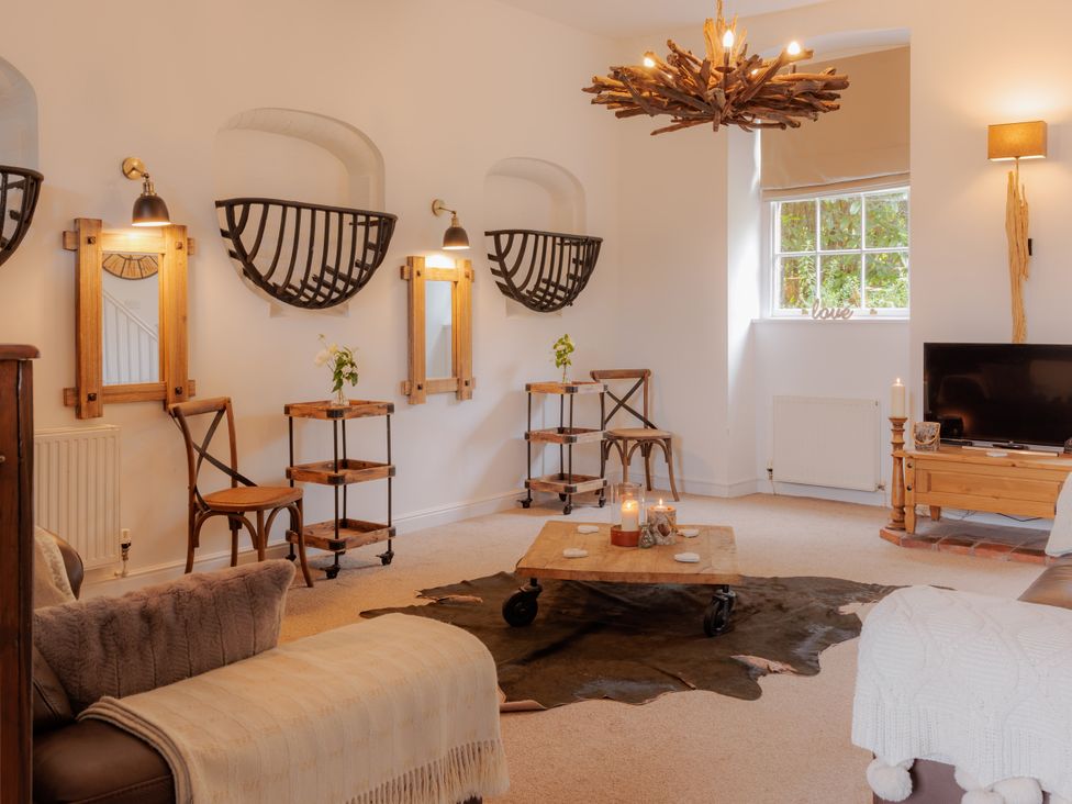 A living room with a chandelier and a television at Stable Cottage in Bridgnorth