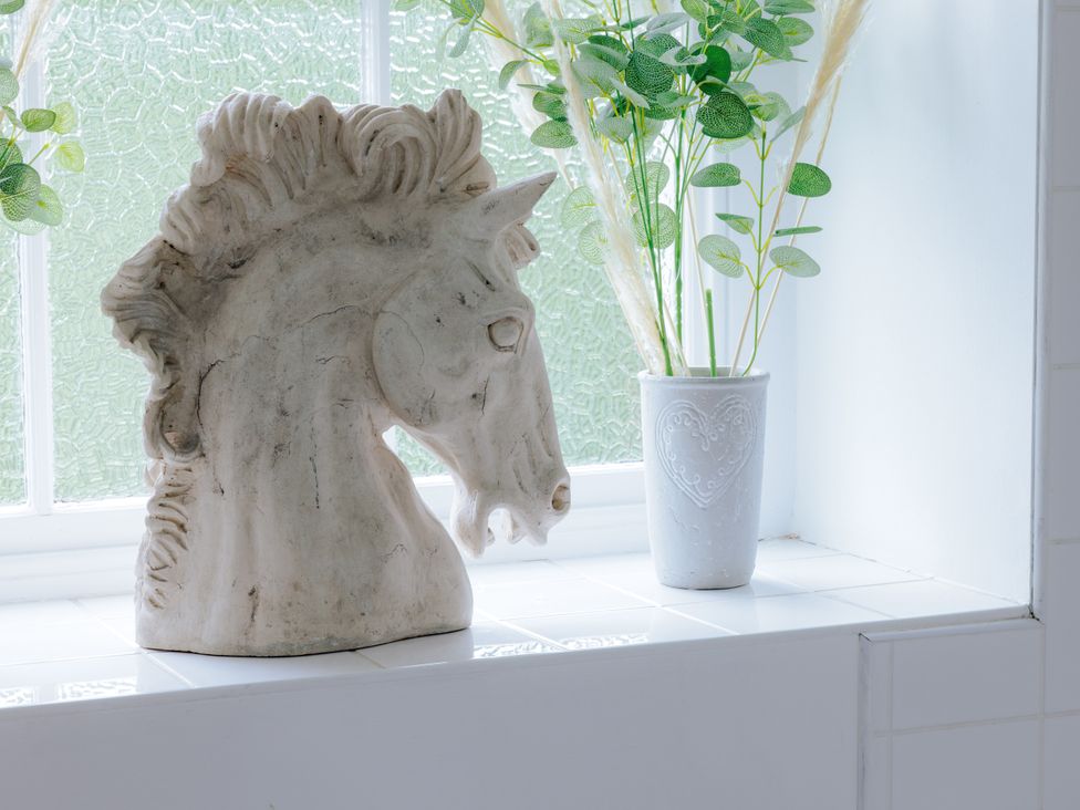 A horse statue and a potted plant on a window sill at Stable Cottage in Bridgnorth