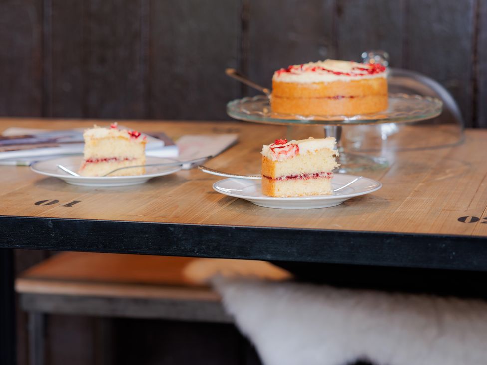A kitchen table with cake and a magazine at Stable Cottage in Bridgnorth