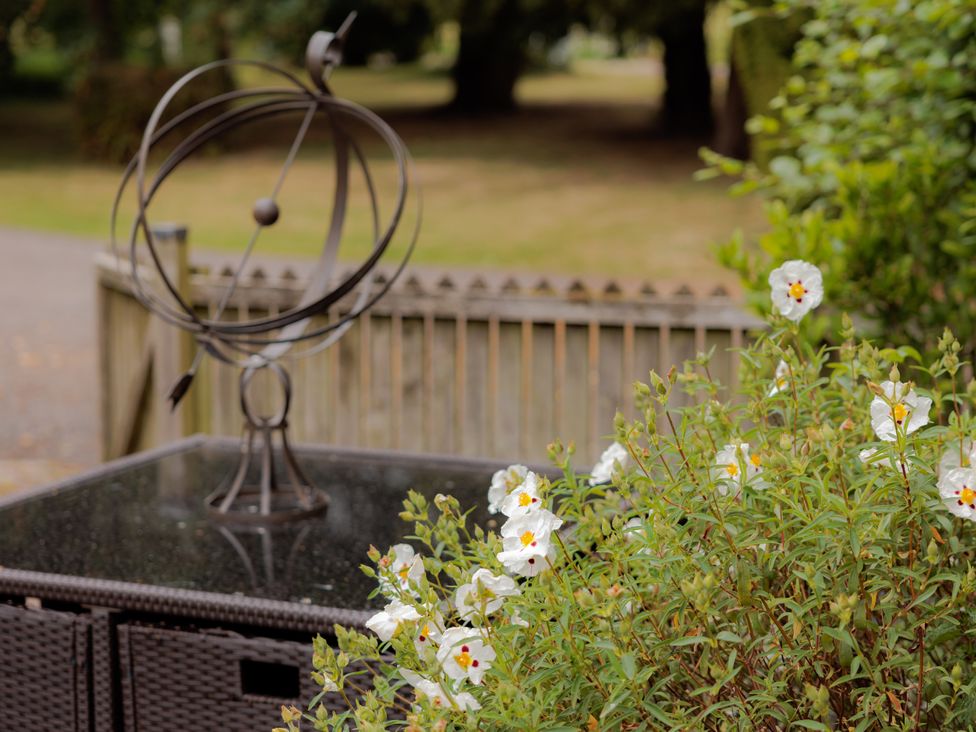 A garden with a sculpture and flowers at Stable Cottage in Bridgnorth