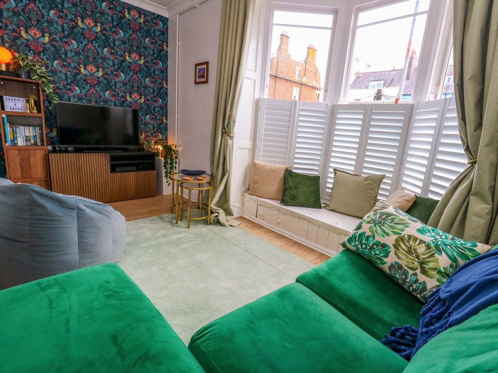 A living room with a television and bookshelf at Seagull & Chips in Weymouth