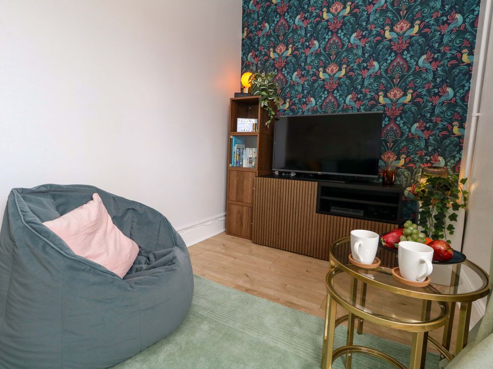 A living room with a bean bag and tv stand at Seagull & Chips in Weymouth