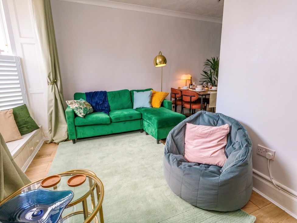 A living room with a green sofa and bean bag at Seagull & Chips in Weymouth