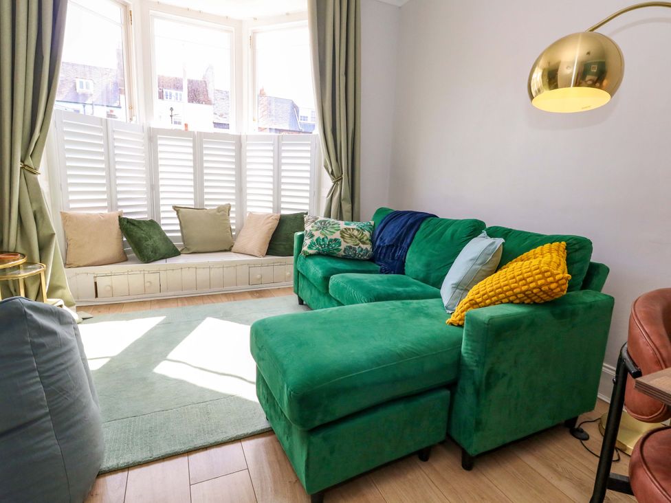 A living room with a green sofa and cushions at Seagull & Chips in Weymouth