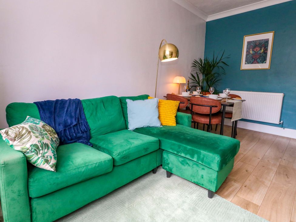 A living room with a green sofa and dining table at Seagull & Chips in Weymouth