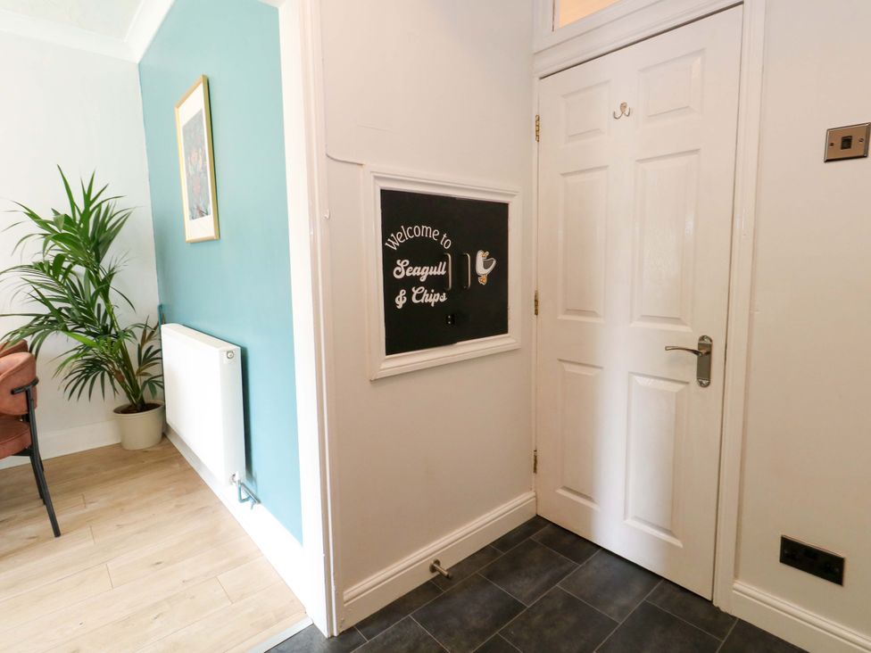 A hallway with a welcome sign and plant at Seagull & Chips in Weymouth