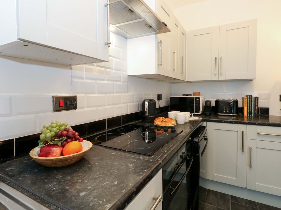 A kitchen with a stove, microwave, and fruit on the counter at Seagull & Chips in Weymouth