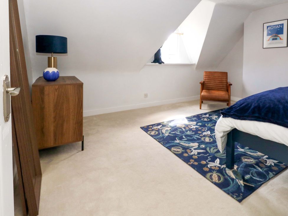 A bedroom with furniture including a bed, side table, and lamp at Seagull & Chips in Weymouth