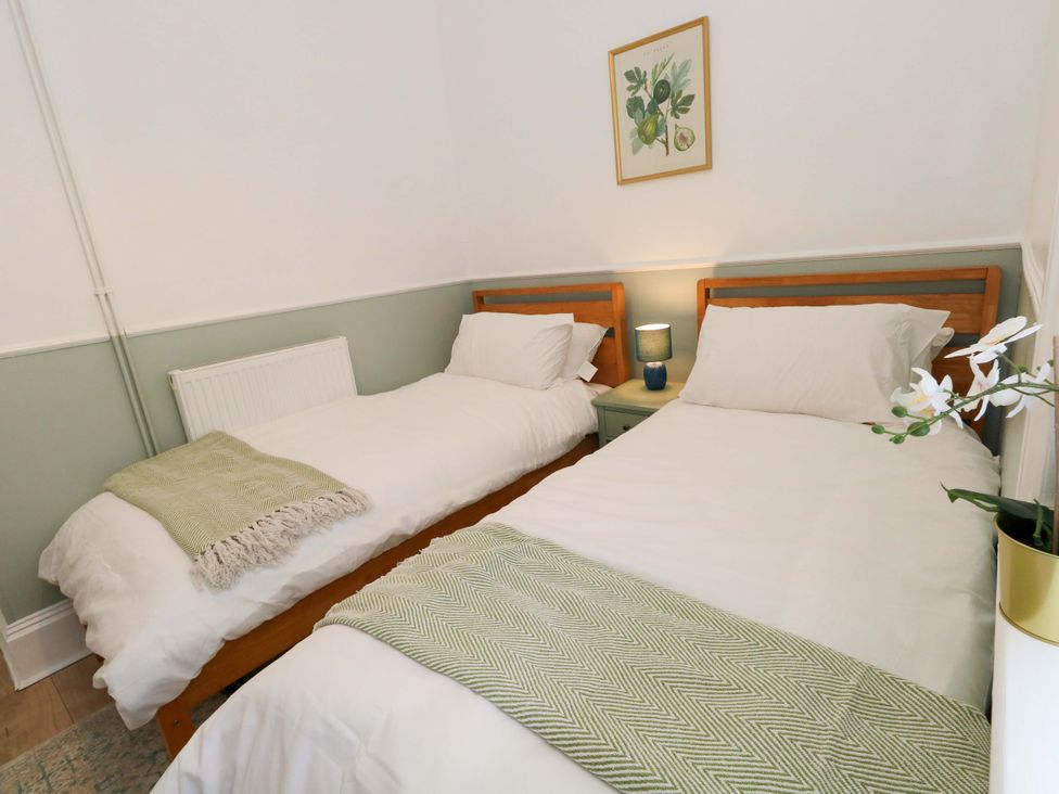 A bedroom with two beds and a bedside table at Seagull & Chips in Weymouth