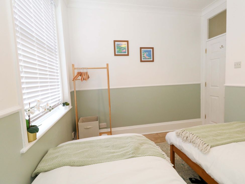 A bedroom with twin beds and a clothes rack at Seagull & Chips in Weymouth