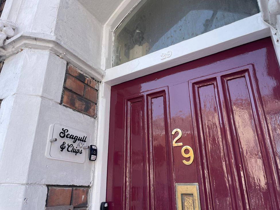 An entryway with a maroon door and nameplate at Seagull & Chips in Weymouth