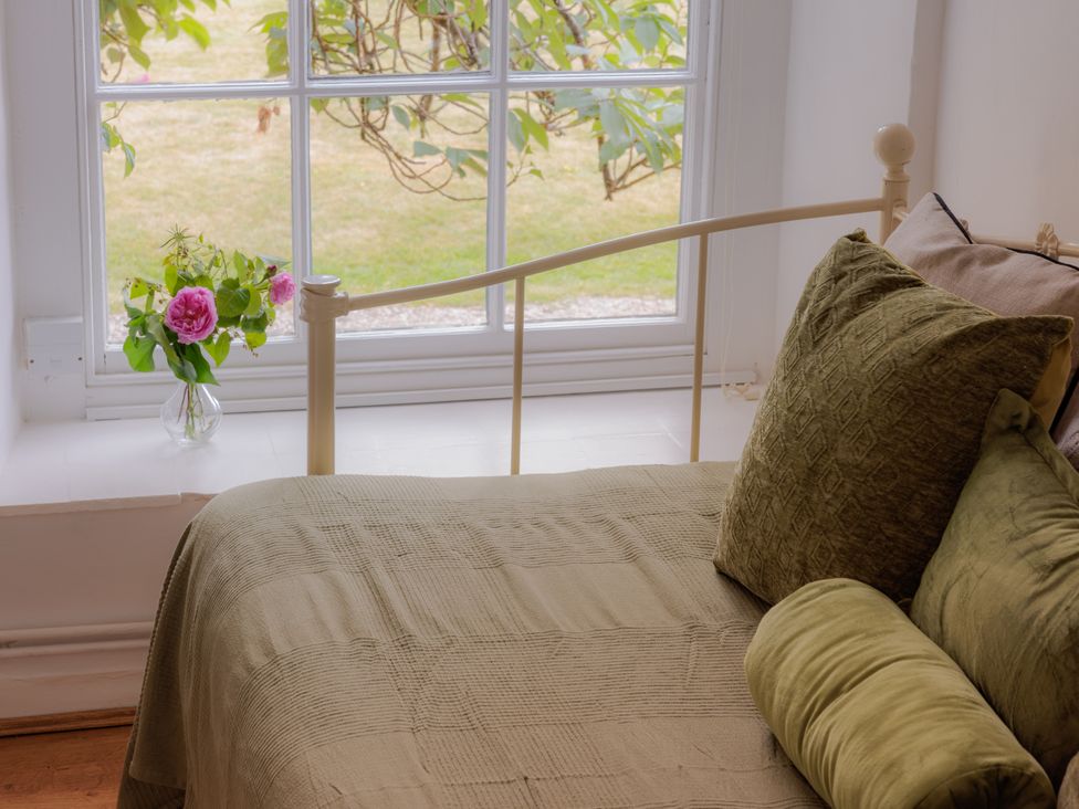 A bedroom with a bed and flowers on the windowsill at Game Cottage in Bridgnorth