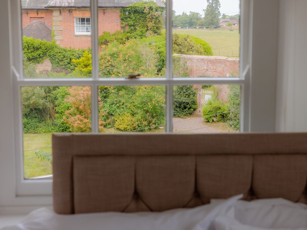 A bedroom with a view of a garden and path at Game Cottage in Bridgnorth