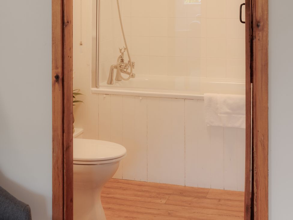 A bathroom with a bathtub and a toilet at Game Cottage in Bridgnorth