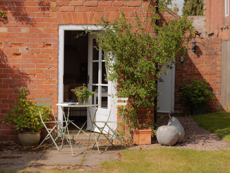 A garden with a table and chairs by a brick wall at The Bothy in Bridgnorth