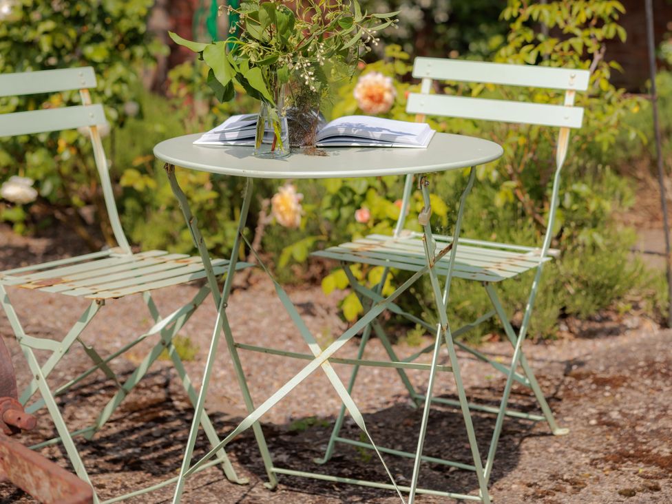 A table and chairs with a vase and a book in the garden at The Bothy in Bridgnorth