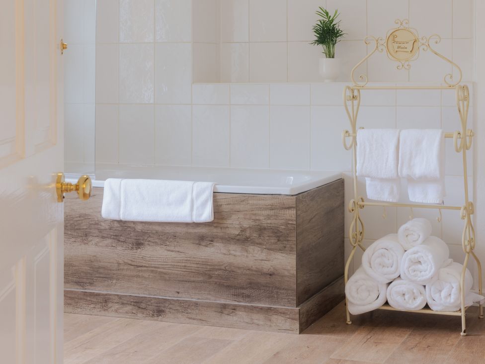 A bathroom with a bathtub and towels on a rack at Carriage Cottage Worfield near Bridgnorth