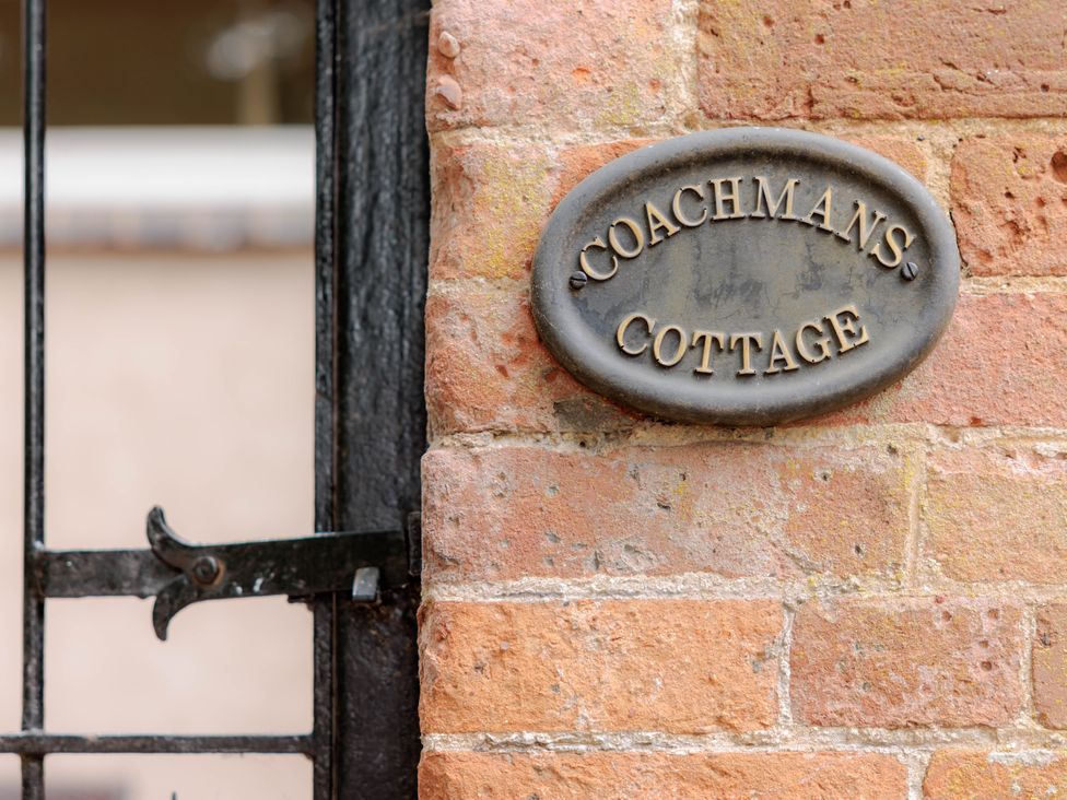 A plaque mounted on a brick wall for Coachmans Cottage in Worfield near Bridgnorth