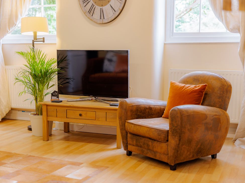 A living room with a television and an armchair at Coachmans Cottage in Worfield near Bridgnorth
