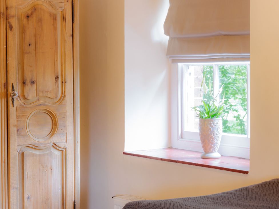 A bedroom with a wardrobe and a plant on a windowsill at Coachmans Cottage in Worfield near Bridgnorth