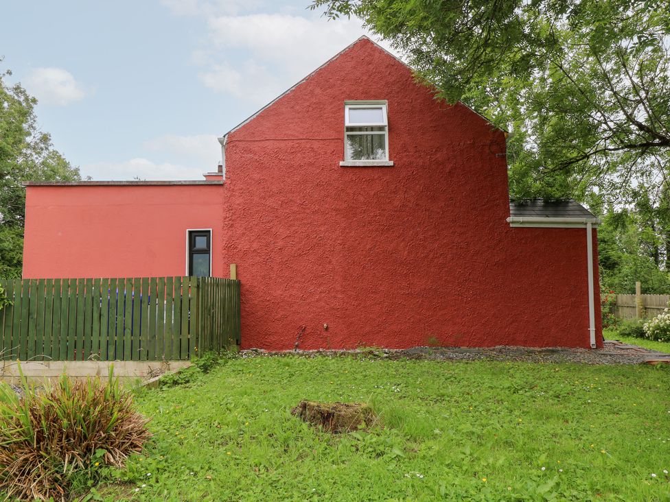 A red house with a fence and grassy area at Huath in Carrick on Shannon