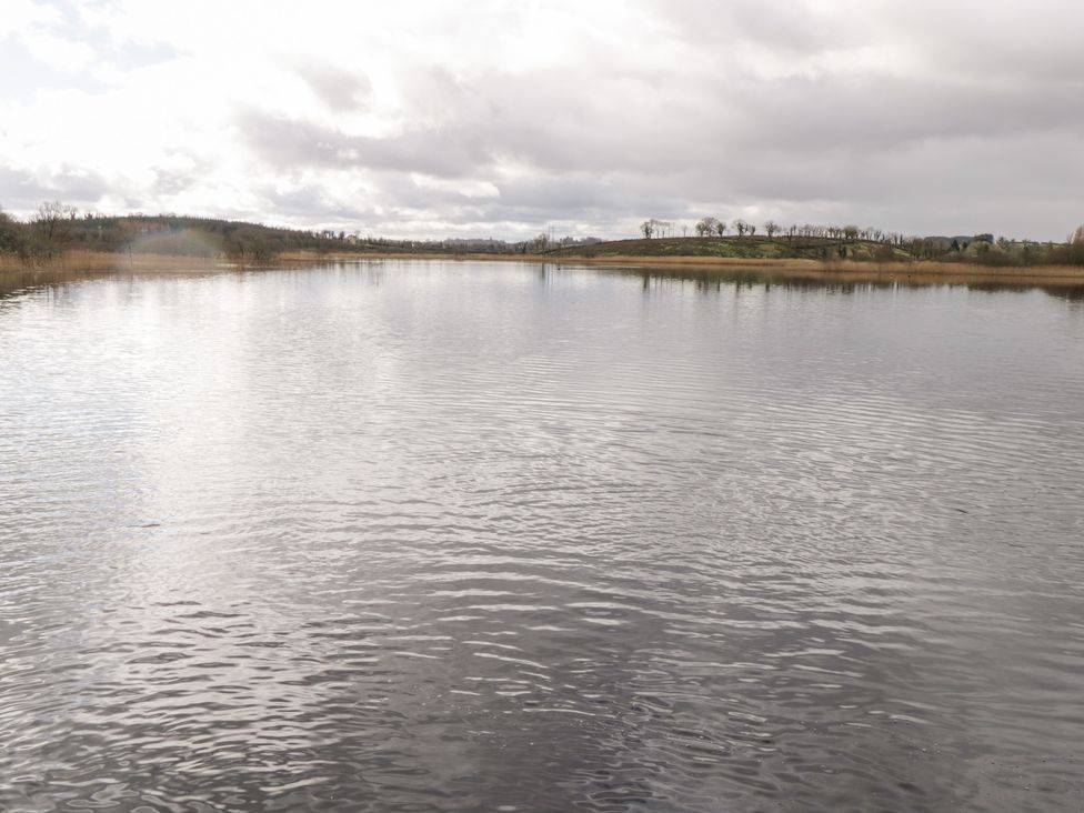 A body of water with surrounding land and cloudy sky at Huath in Carrick on Shannon