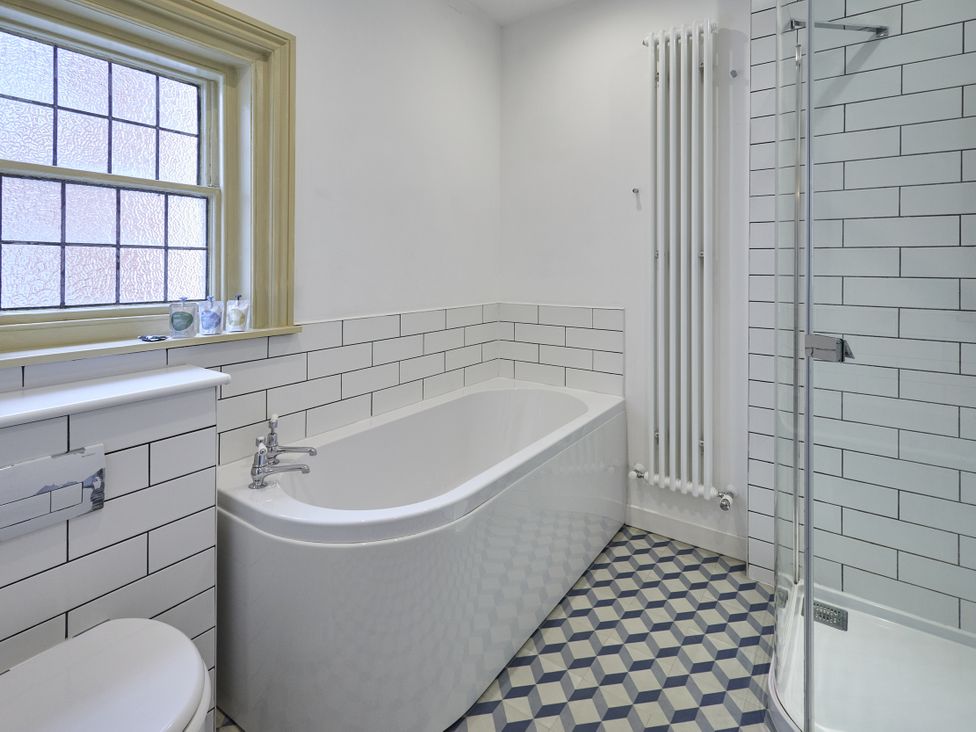 A bathroom with a bathtub, shower, and window at Beachside Cottage in Sandsend