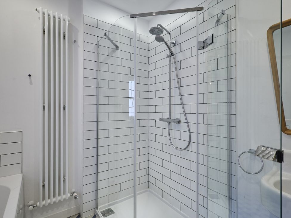 A shower enclosure with glass doors and tiles at Beachside Cottage in Sandsend