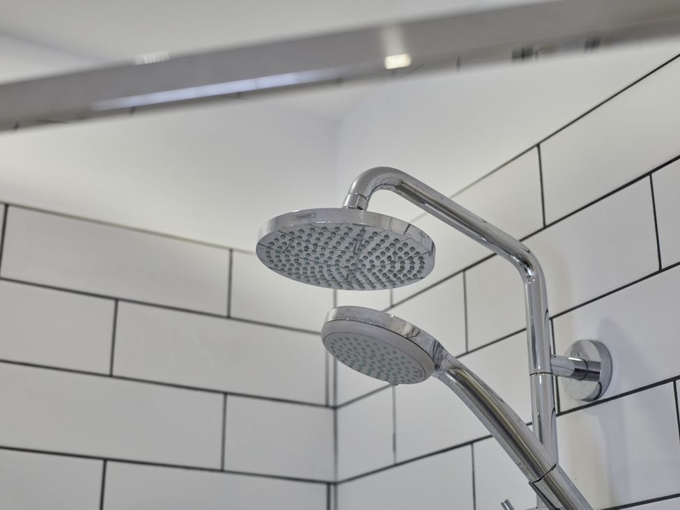 A shower head and wall tiles at Beachside Cottage in Sandsend