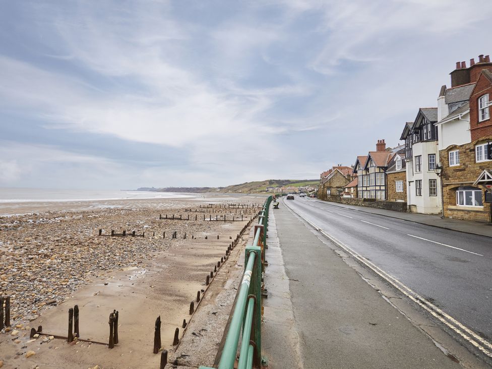 A beach with a road and houses at Beachside Cottage in Sandsend